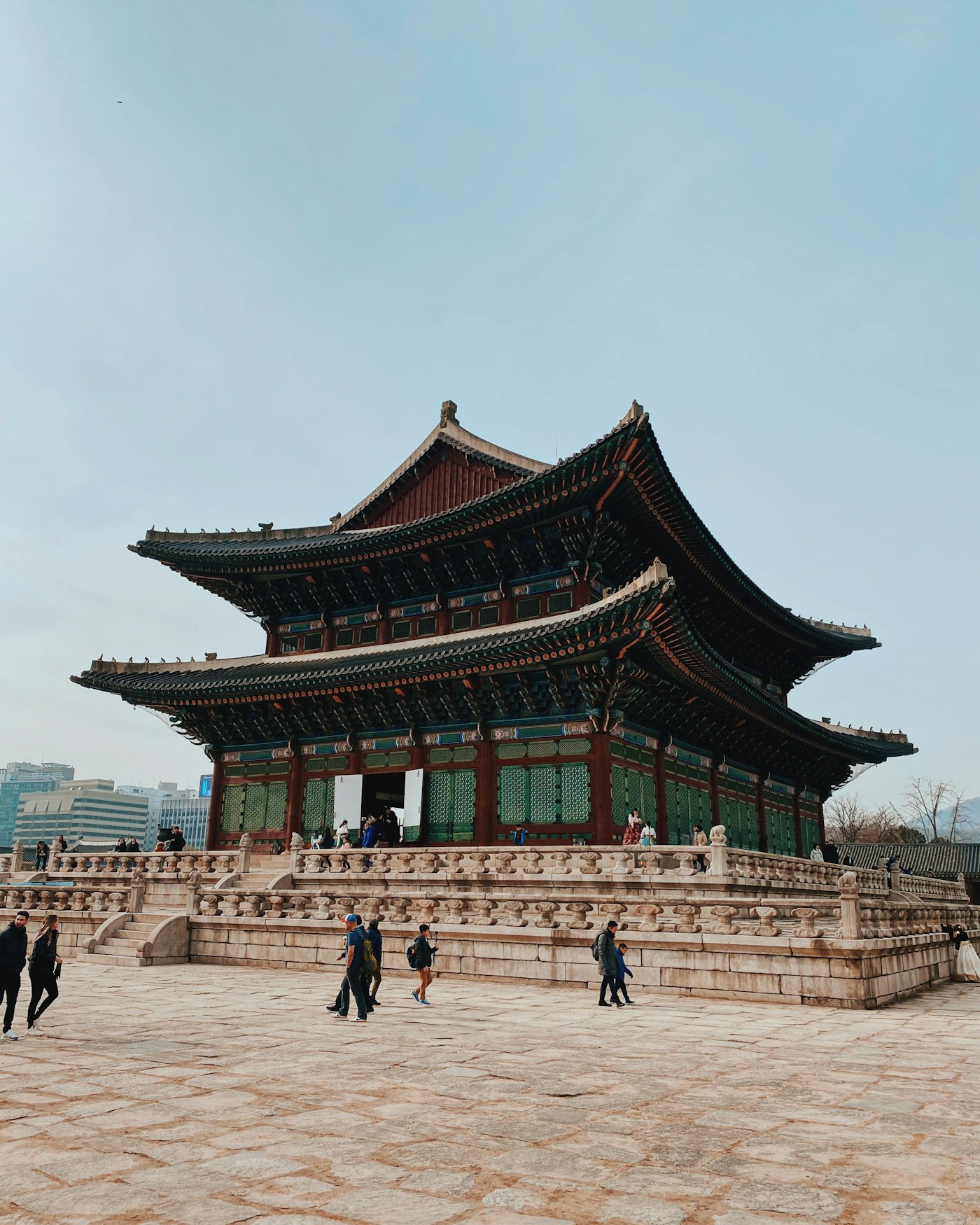 Visitors crossing the stone courtyard of Gyeongbokgung Palace in Seoul